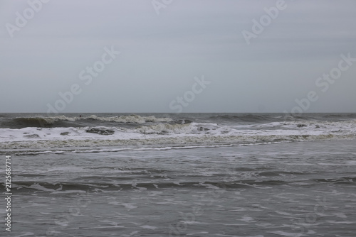 Fotografie Atlantic Ocean surf at Folly Beach, South Carolina on a gray day in March under heavy clouds and cool temperatures