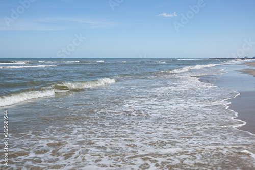 Принти на полотні Atlantic Ocean waves rolling ashore a beach on a calm, clear day with blue sky