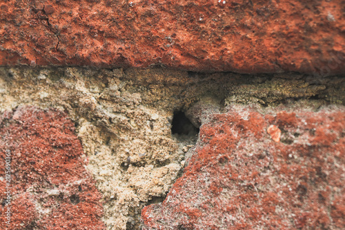 Historic old redbrick wall with mortar eroded with age. 