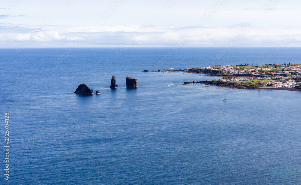 Fototapeta premium Mosteiros, San Miguel Island, Azores. Rock formations along the Atlantic coastline. Small coastal town in the background. Clear blue ocean waters.