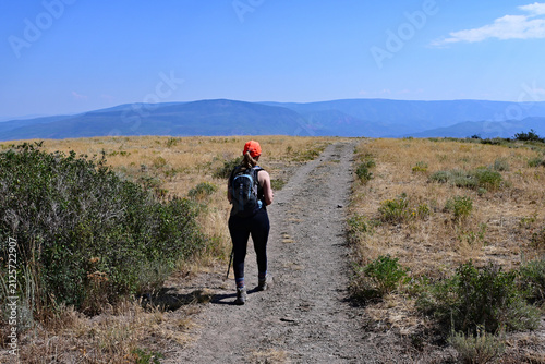 Woman hikes along exposed section of Thomas Lakes Trail in White River National Forest near Carbondale, Colorado on sunny summer morning.