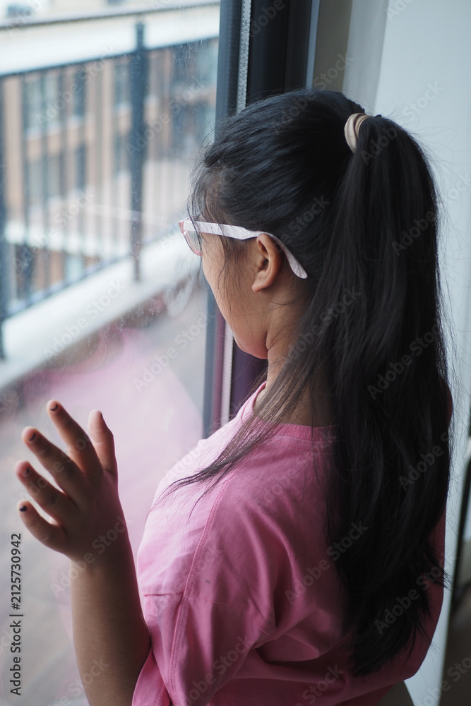 Obraz premium Child looks out the window while standing in a room