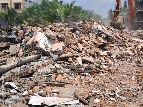 Heavy excavator demolishing a building with rubble and debris on site