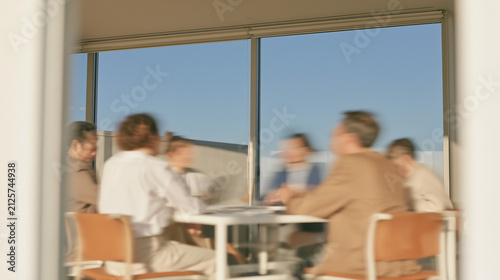 Blurred businessmen in motion during a glass meeting room discussion