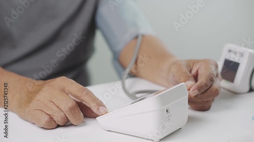 Close-up of a senior adult using a digital blood pressure monitor at home to check blood pressure and cardiovascular health. Healthcare monitoring, hypertension prevention, self care and healthy aging