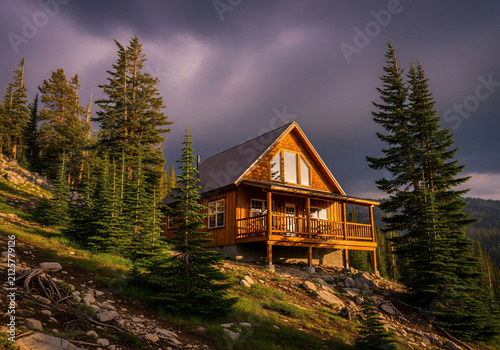 Wooden mountain cabin nestled in a pine forest at sunset