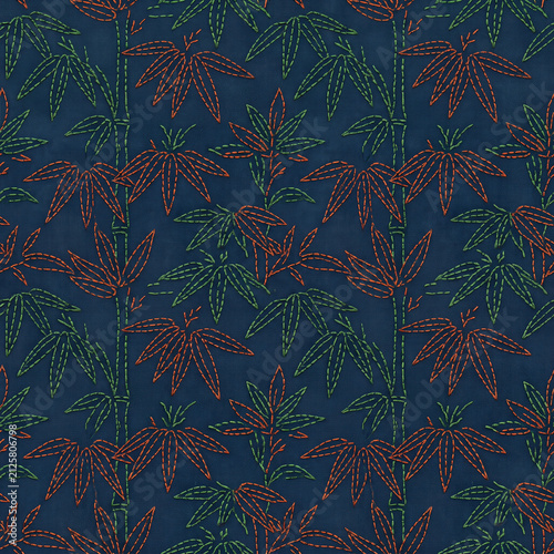 Japanese textile pattern featuring traditional embroidery sashiko style with bamboo stalk and leaf motifs on dark blue indigo background fabric texture