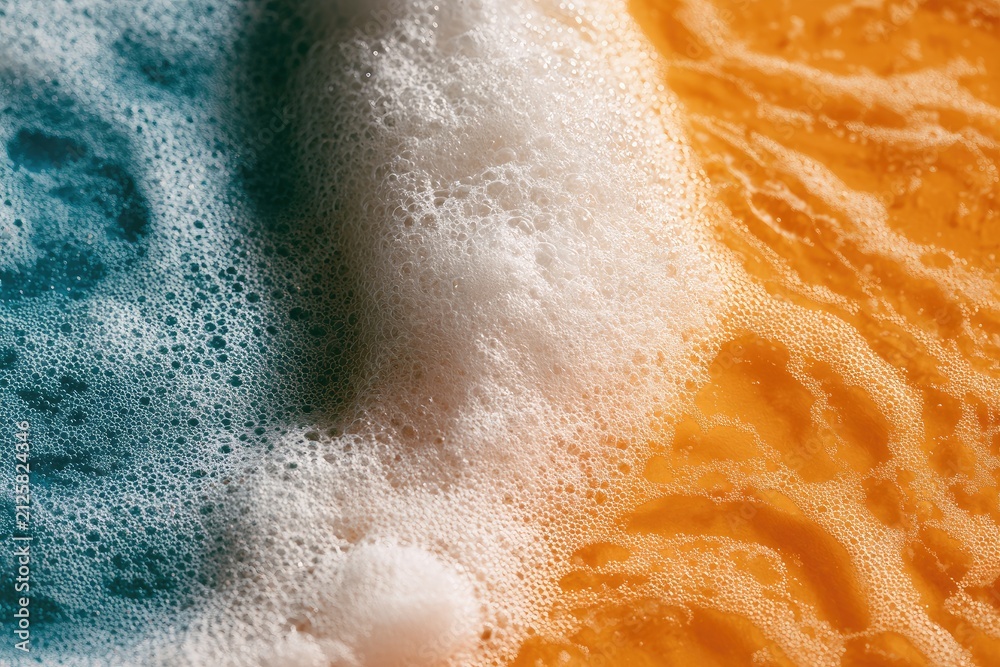 Fototapeta premium Macro shot of white foam meeting vibrant orange and teal liquid surfaces