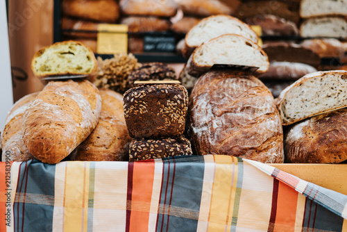 A market stall is filled with various types of artisanal breads, including loaves and rolls.