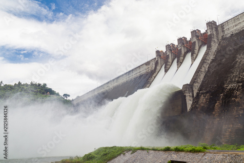 Obraz na płótnie Hydroelectric Dam Spillway Releasing Water Under Cloudy Sky