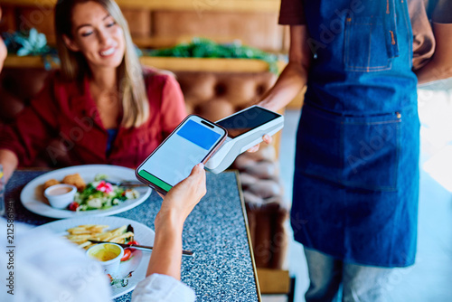 Canvastavla Customer paying restaurant bill with mobile phone, holding it over a payment ter