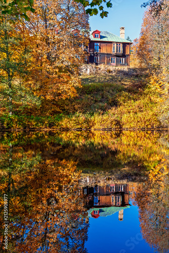 Lake with a house on a hill with water reflections and autumn colors