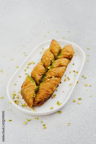 Принти на полотні Turkish pistachio baklava served on a white plate with scattered nuts