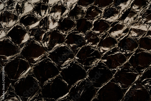 Dark exotic reptile leather texture with glossy python scales for luxury fashion background