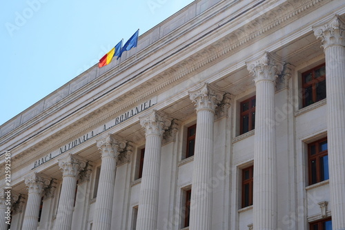 Facade of The National Bank of Romania neoclassical building with the Romanian and the European Union flags