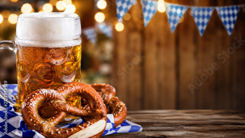 Background for Oktoberfest promotions and pub ads. Beer mug and pretzel on a wooden table.
