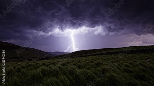 Dramatic Lightning Strikes Over Grassy Hills During Thunderstorm