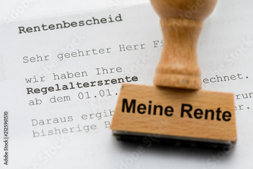 Ein Holzstempel ist beschriftet mit dem Aufdruck: Meine Rente und liegt über einem Rentenbescheid