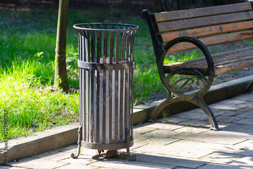 Public waste bin and park bench in a clean urban park