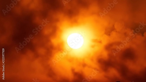 Fiery Sun Breaking Through Clouds Over City Skyline at Sunset