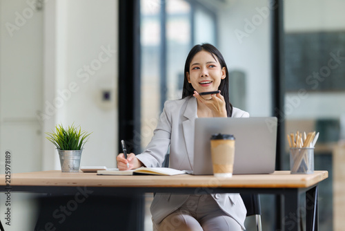 Canvastavla Asian businesswoman making a phone call on speaker, dictating notes and multitas