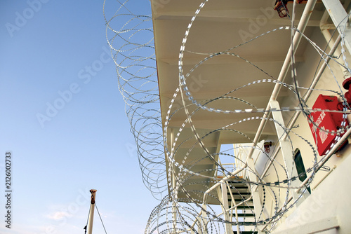 Barbed or razor wire attached to the ship hull, superstructure and railings to protect the crew against piracy attack passing Gulf of Guinea in West Africa.