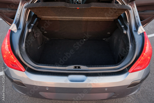 Open trunk of a modern gray hatchback car showing empty luggage compartment and cargo space in a parking lot.