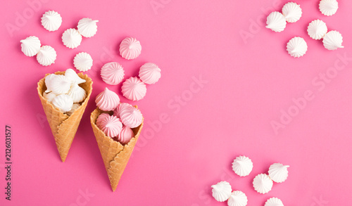 Ice cream cones with white and pink meringue on a pink background. Top view. Copy space.