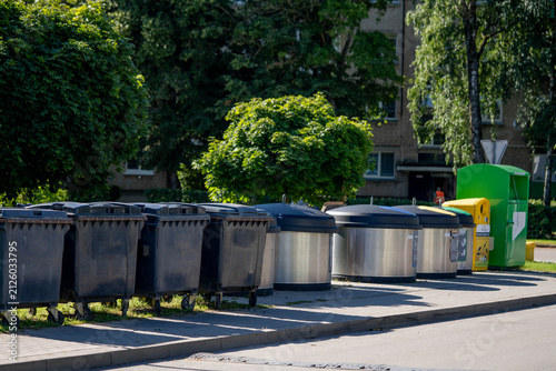 Fotografie Waste disposal bins in urban area with trees and residential buildings in backgr