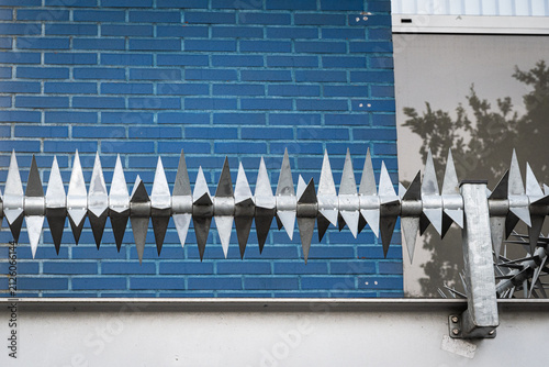 Konstfotografi Metal security spikes on a blue brick wall