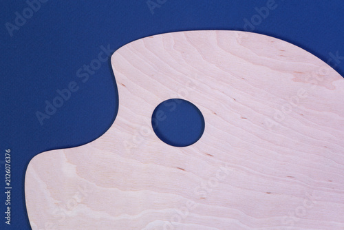 close up of clean wooden artist's palette laying on blue cardboard