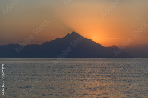 Sun rising directly behind the peak of Mount Athos with golden rays across the Singitic Gulf, seen from Sithonia, Halkidiki, Greece