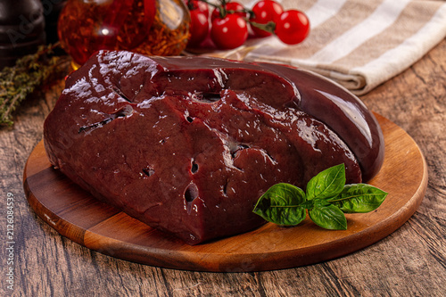 Canvastavla Raw beef liver on wooden board with basil and cherry tomatoes