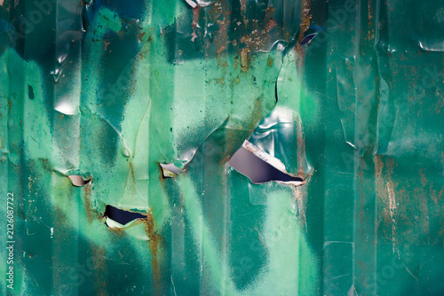 Cuadro en lienzo Weathered green corrugated metal sheet featuring jagged holes and rusted texture