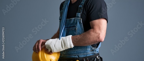 Injured construction worker with bandaged arm and safety helmet