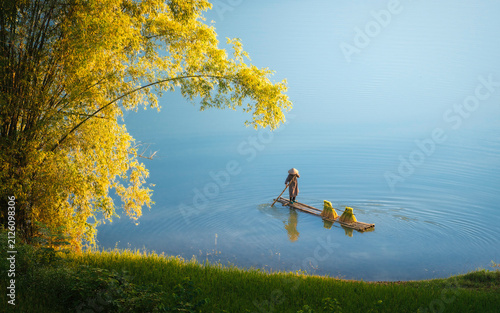 Konstfotografi Local farmer paddling a bamboo boat loaded with harvested sticky rice on Quay So