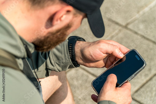 Bearded man in a black cap using his smartphone