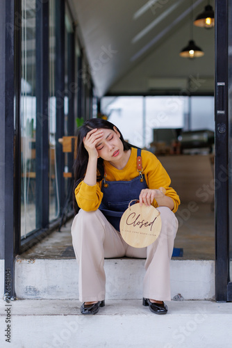 Принти на полотні Stressed small business owner sitting outside store with closed sign, feeling ti