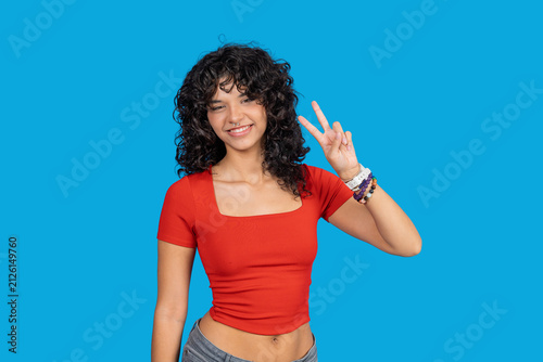 Young woman showing peace sign smiling against blue background
