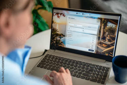 Woman setting search filters on travel booking website via laptop.