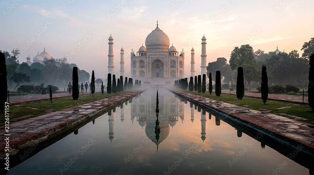 Obraz premium Beautiful Taj Mahal monument in Agra, India, during a calm sunrise with a clear reflection in the water pool of the historic garden courtyard under a soft morning sky