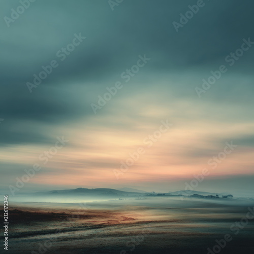 Misty landscape calming background soft blur muted color dawn sky foggy field with distant hill and pastel light over open rural ground, serene natural scenery