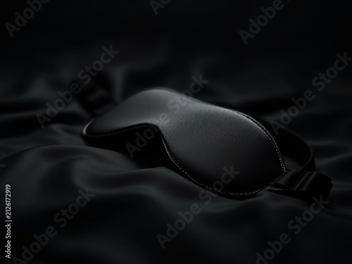Black Sleep Mask Resting on Silky Fabric for Deep Relaxation