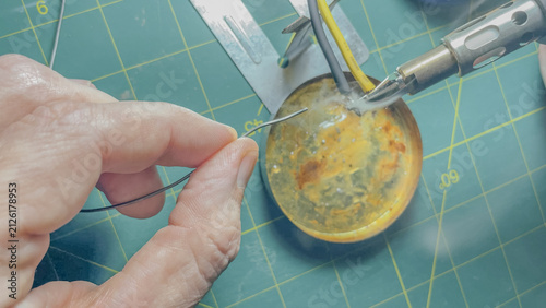 Fotografie Close up of technician hands soldering electric wires with gas iron tip, solder