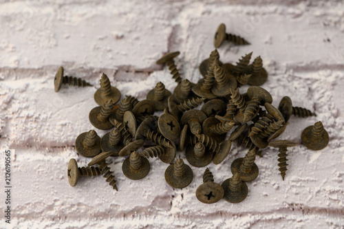 Foto A variety of aged screws lies haphazardly across a weathered brick background, each one telling a story of its past