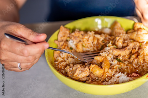 Canvastavla Close-up of a person eating a rice and chicken dish from a bowl with a fork