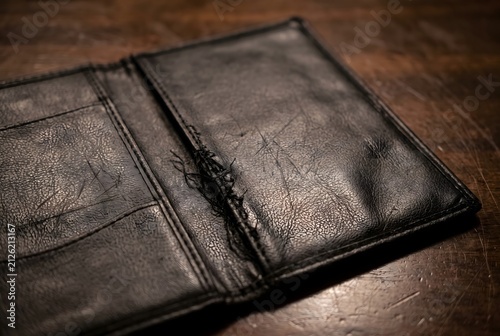 Close up of a black faux-leather guest check presenter showing slightly frayed stitching and scuffs