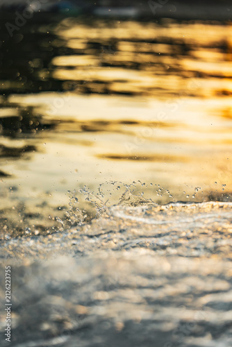 Принти на полотні Glowing water droplets captured above a sunlit wave