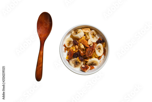 Top down view of a bowl of yogurt topped with banana slices and nuts next to a wooden spoon, PNG isolated on transparent background