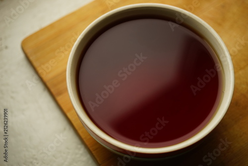 Large ceramic cup with black ceylon tea on wooden board